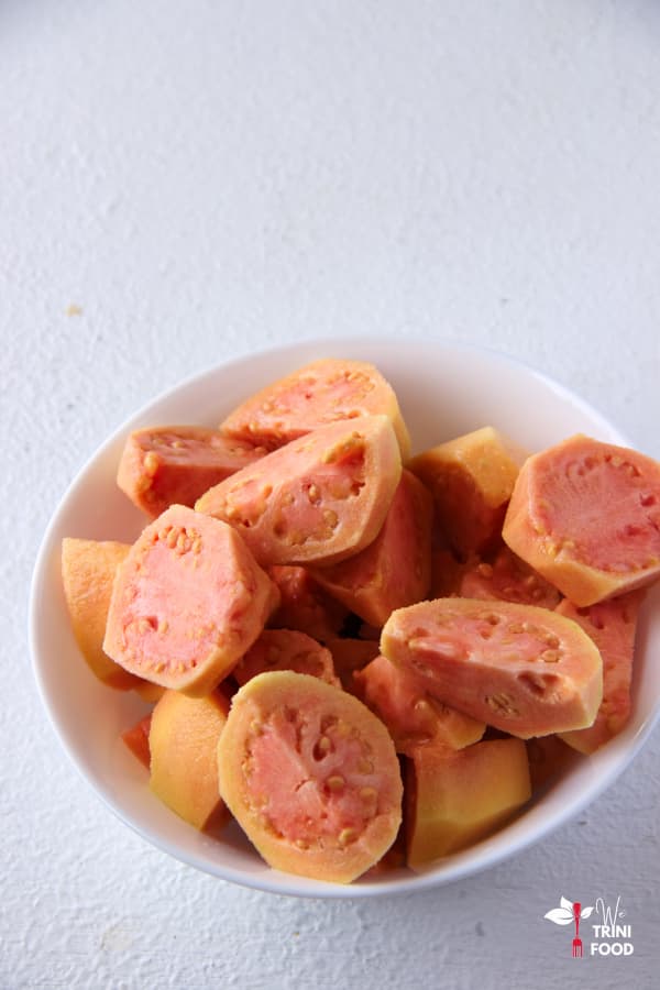 peel and quartered pink guavas in a white bowl