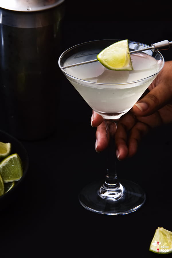 holding a daiquiri drink in a martini glass with lime wedge