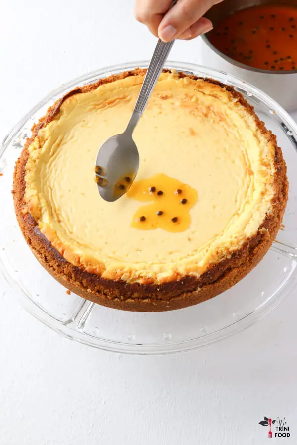 spoon topping onto passion fruit cheesecake