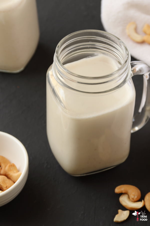cashew milk in a small mason jar with cashews on both sides