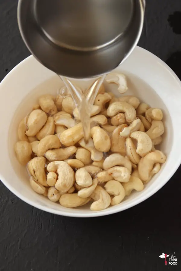 boiling water being poured over cashews in a while bowl