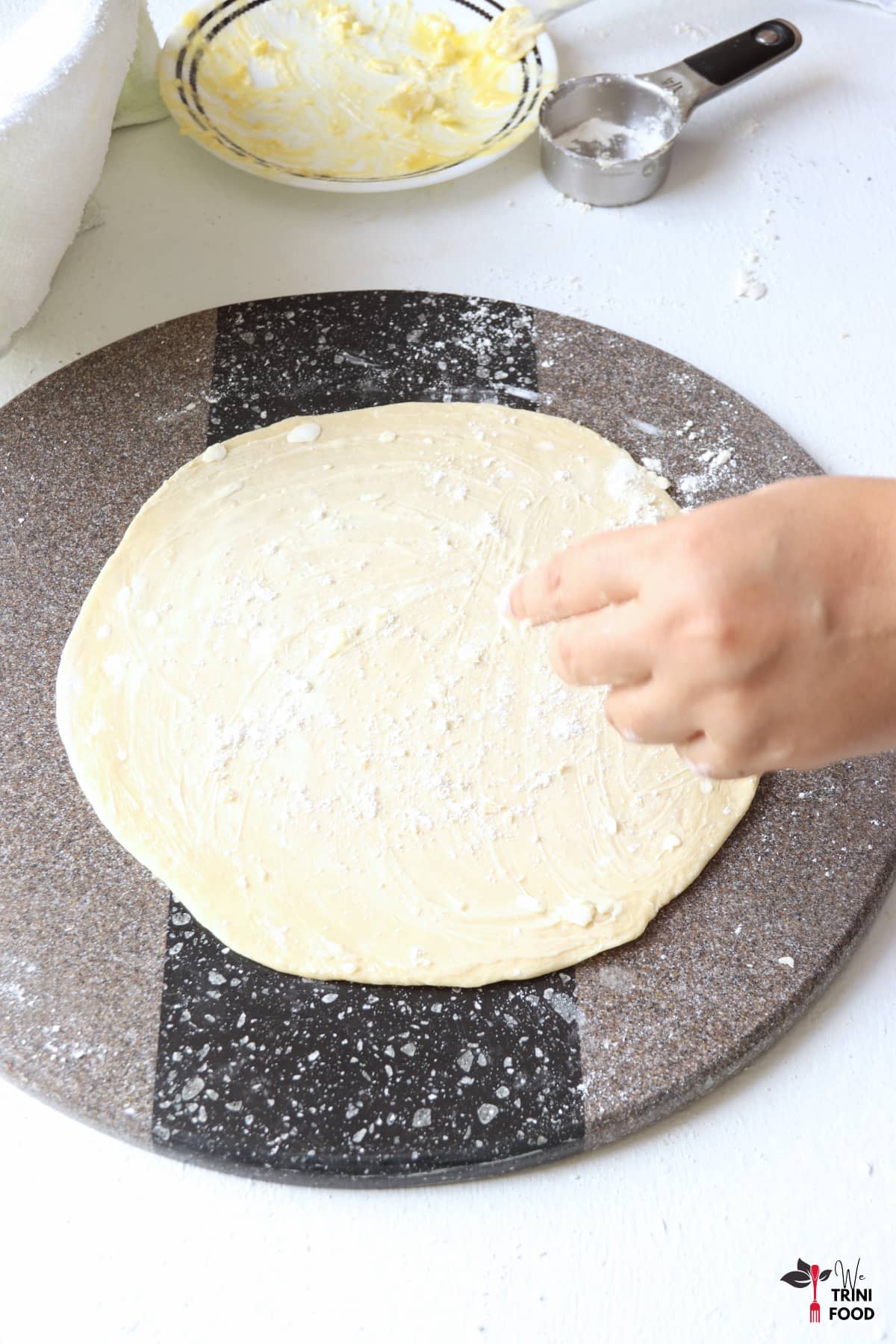 sprinkle flour over the buttered roti on a gray rolling surface