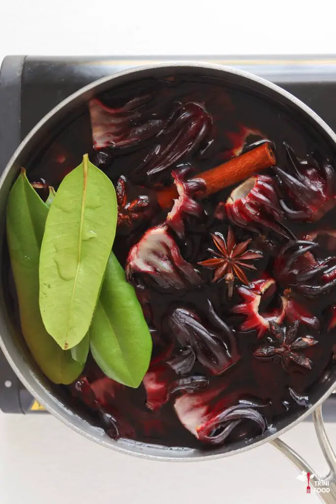 sorrel, star anise, cinnamon stick, bay leaves in a pot on the stove for making sorrel drink