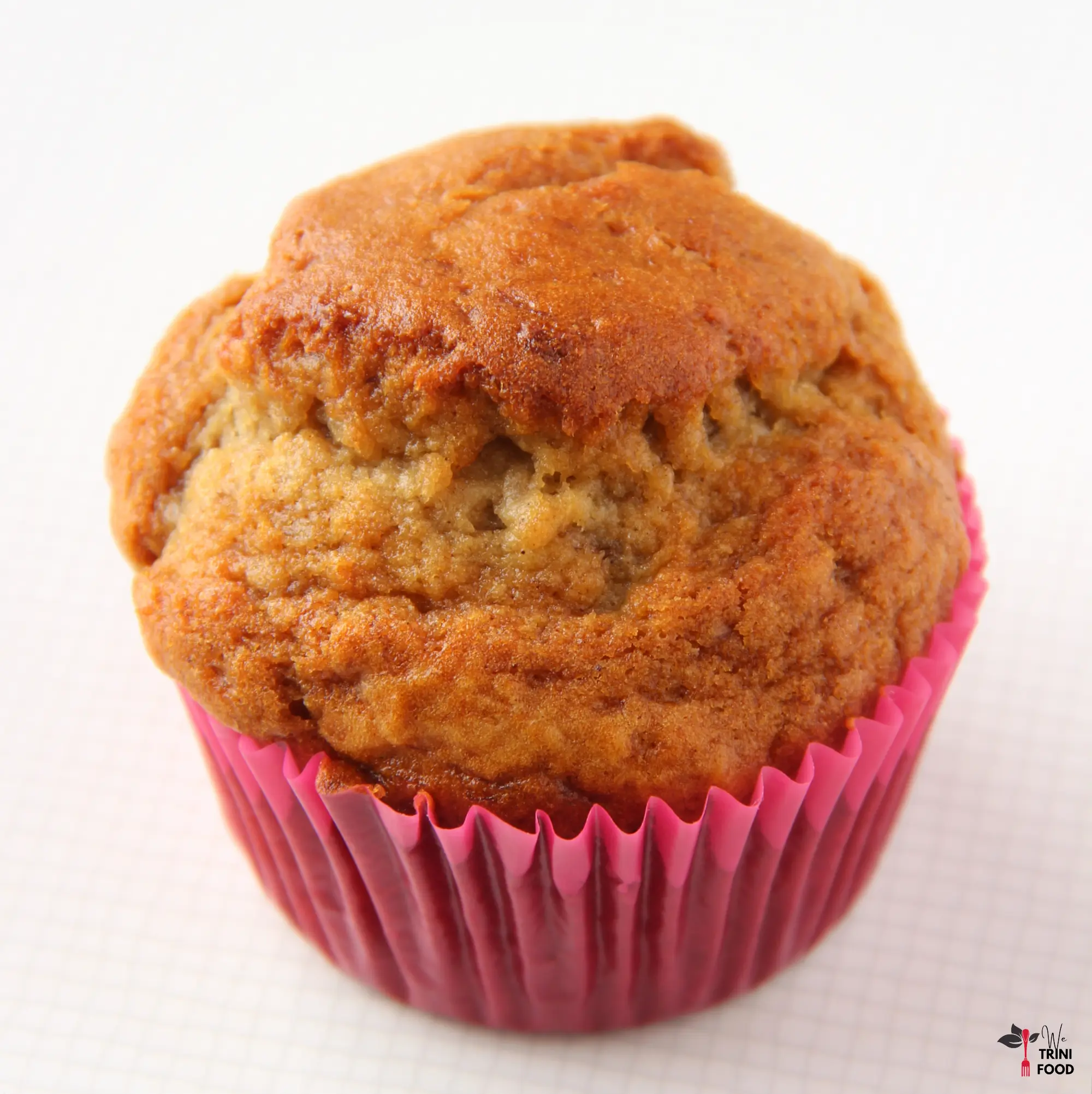 baked banana bread muffin in a pink cupcake wrapper on a white background