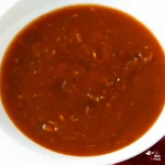 trinidad bbq sauce with freshly grated garlic and Caribbean green seasoning in a white bowl