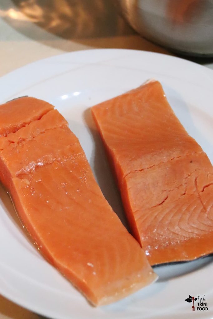2 raw salmon fillets with skin on a white plate