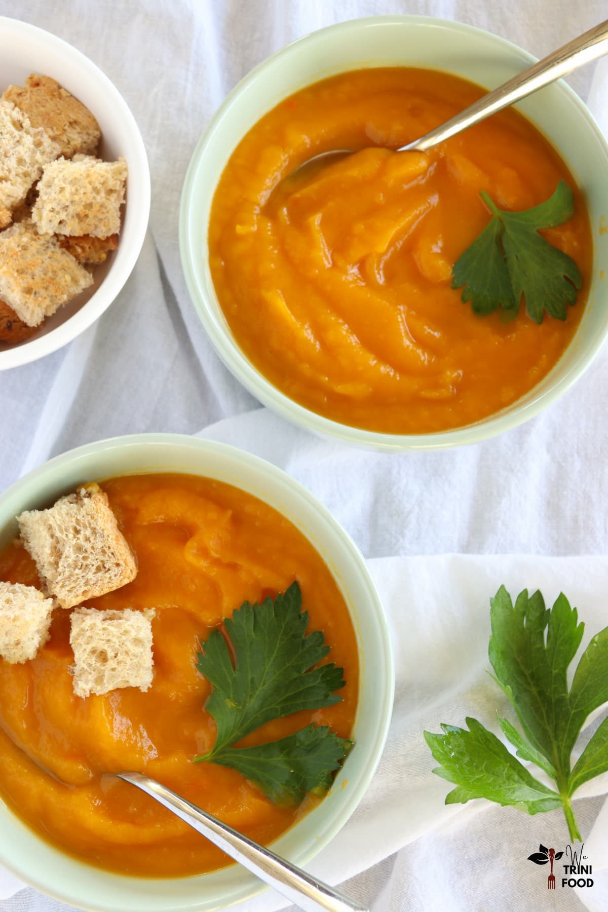butternut squash with sweet potatoes and carrot in bowls with cilantro leaves and homemade croutons