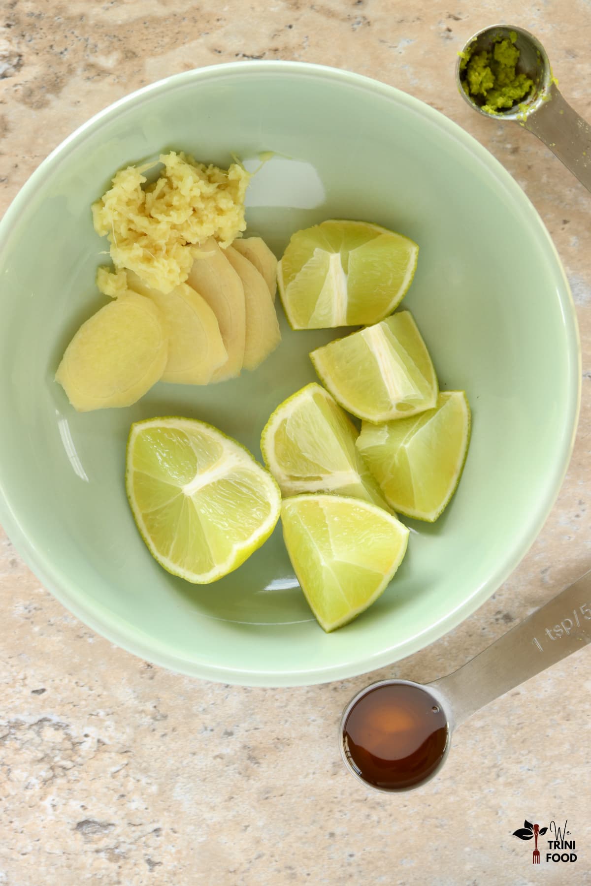 Ingredients for a ginger lime honey drink: grated ginger, lime wedges, honey and zest in a green bowl