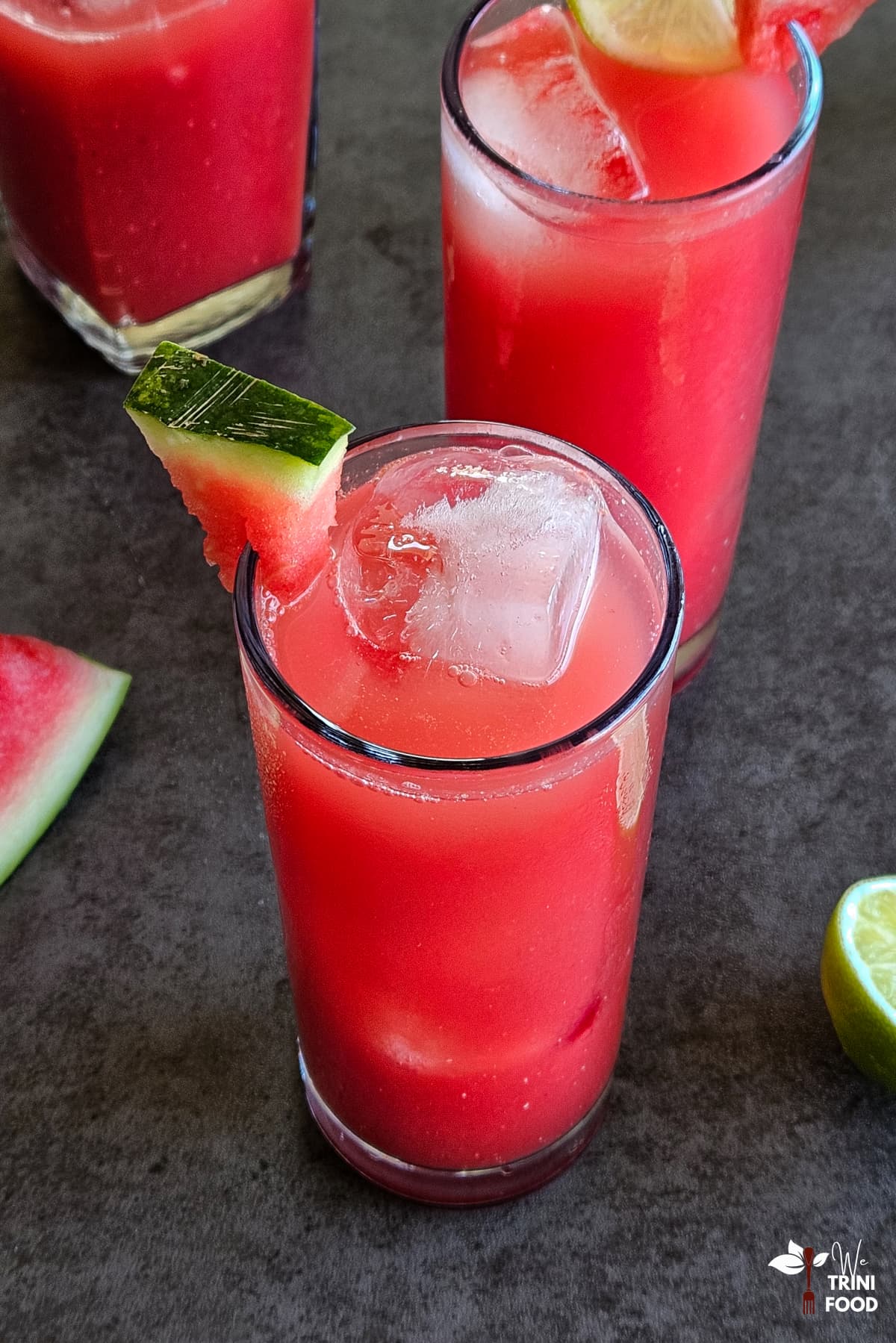 watermelon juice in 3 glasses garnished with watermelon wedge and ingredients on the side