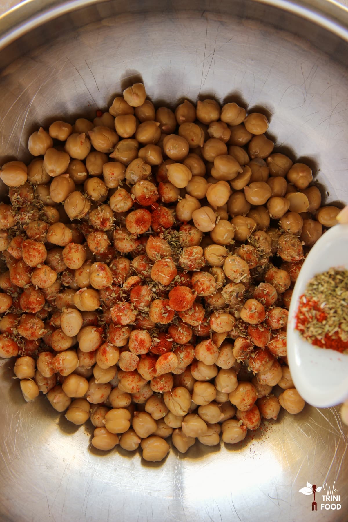 seasoning chickpeas with cayenne, oregano and salt before roasting