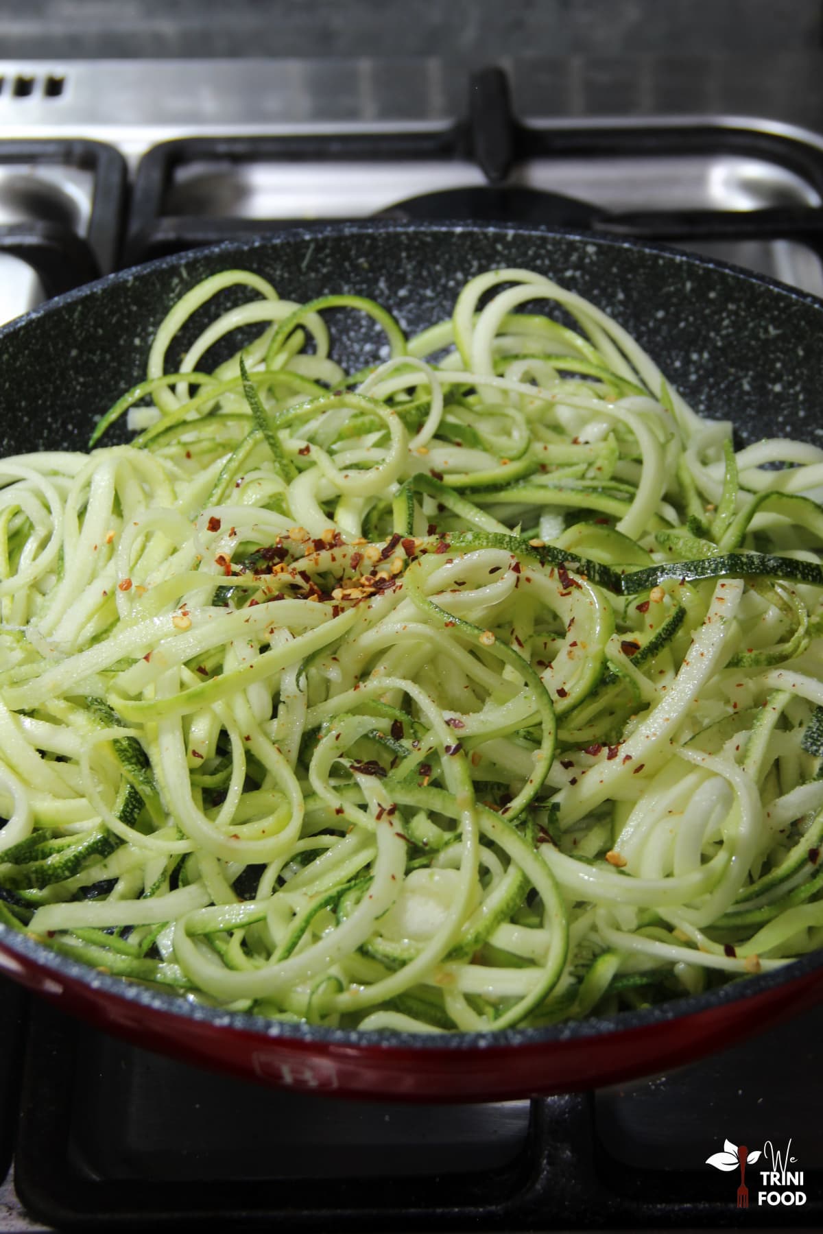 adding seasoning to zucchini noodles and garlic