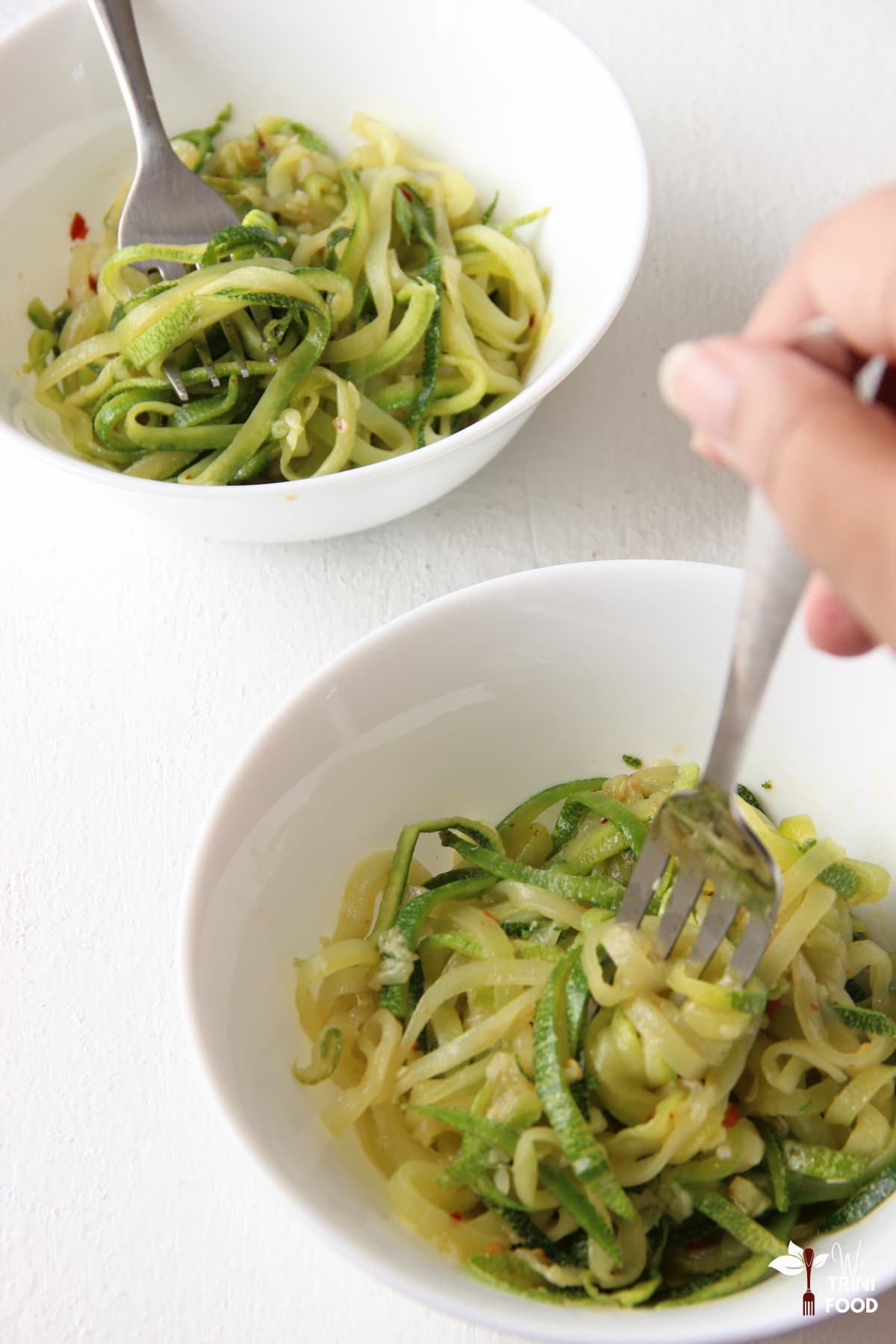 serving zucchini noodles in white bowls