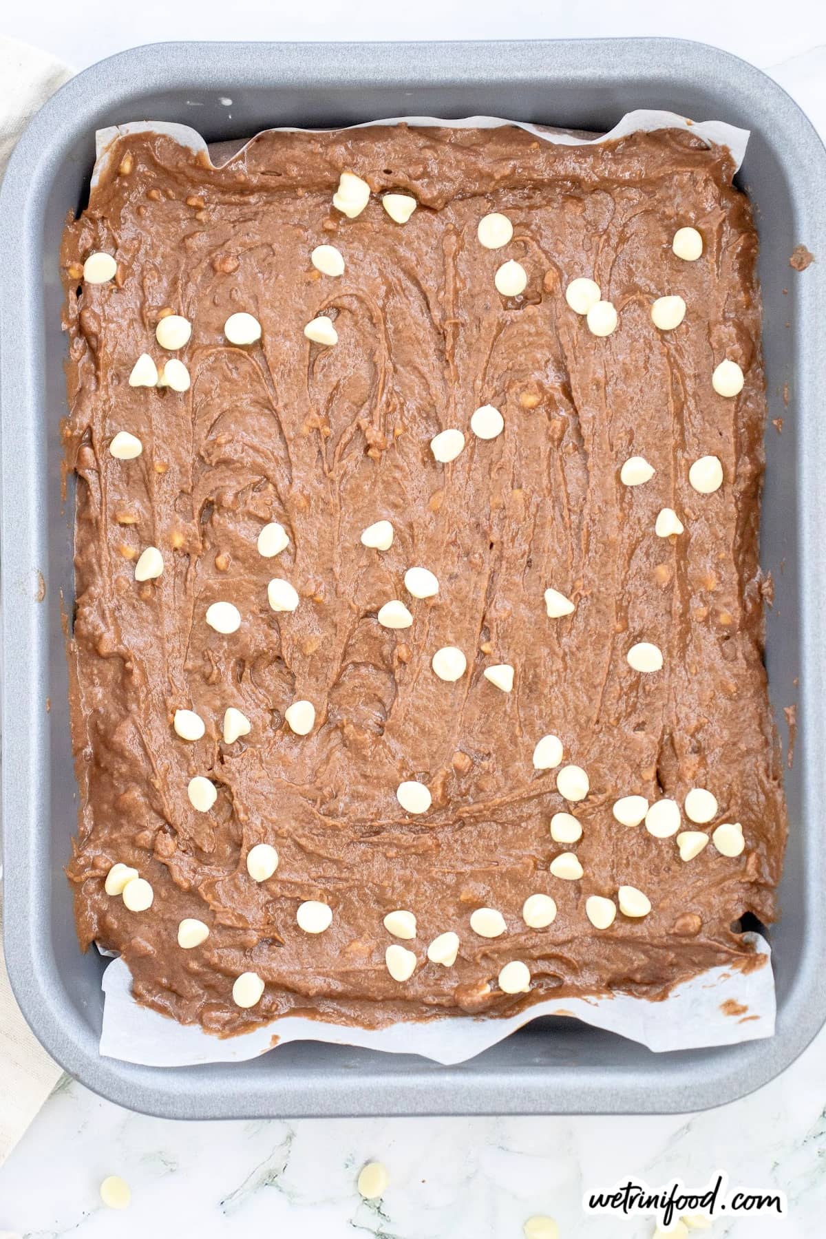 raw sweet potato brownies in baking tray with white chocolate chips on top