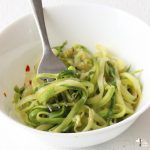 zucchini noodles with garlic in white bowl with red pepper flakes
