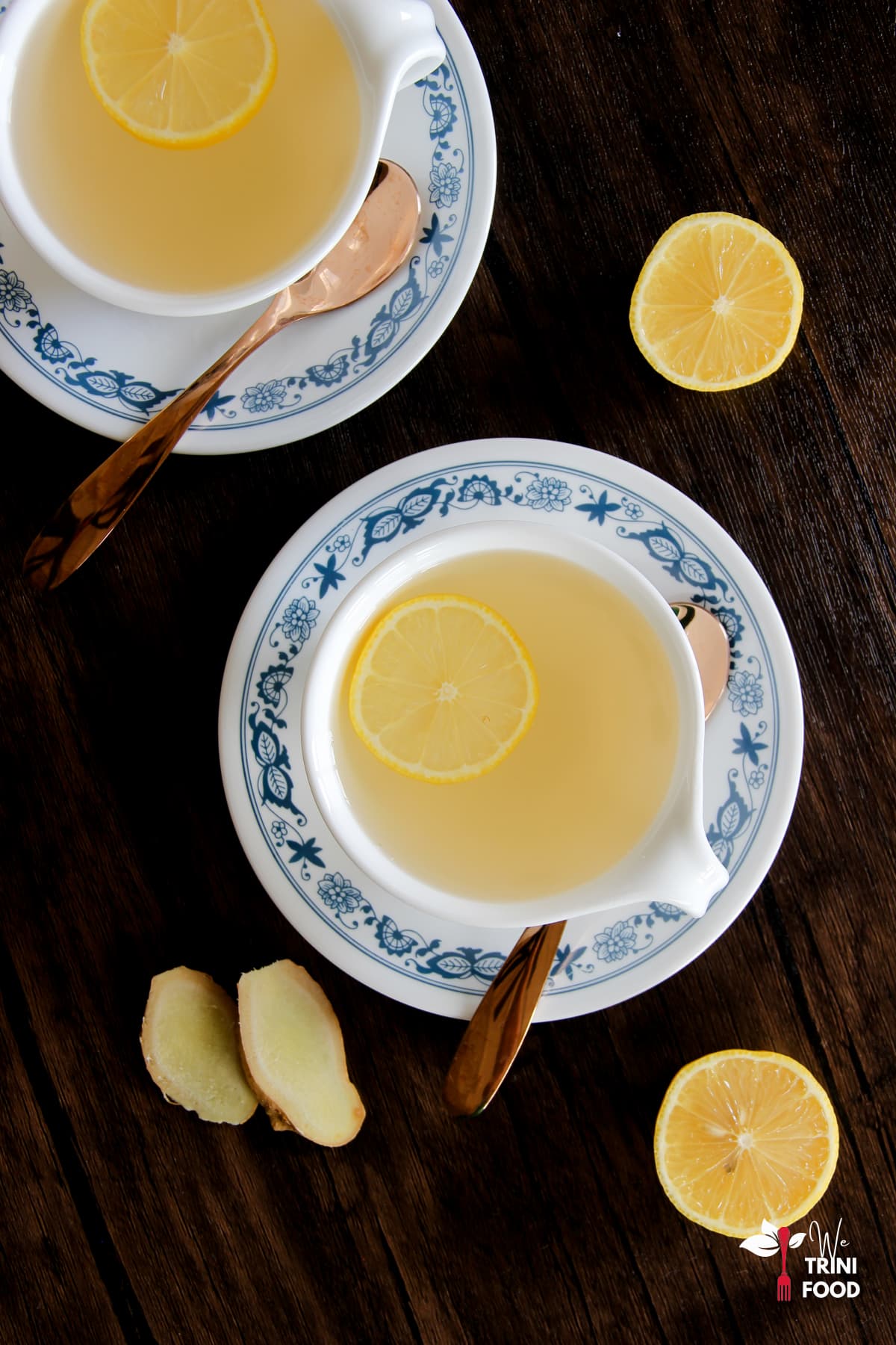 ginger and lemon tea in teacups with lemon slices and lemon halves and ginger slices around the teacups