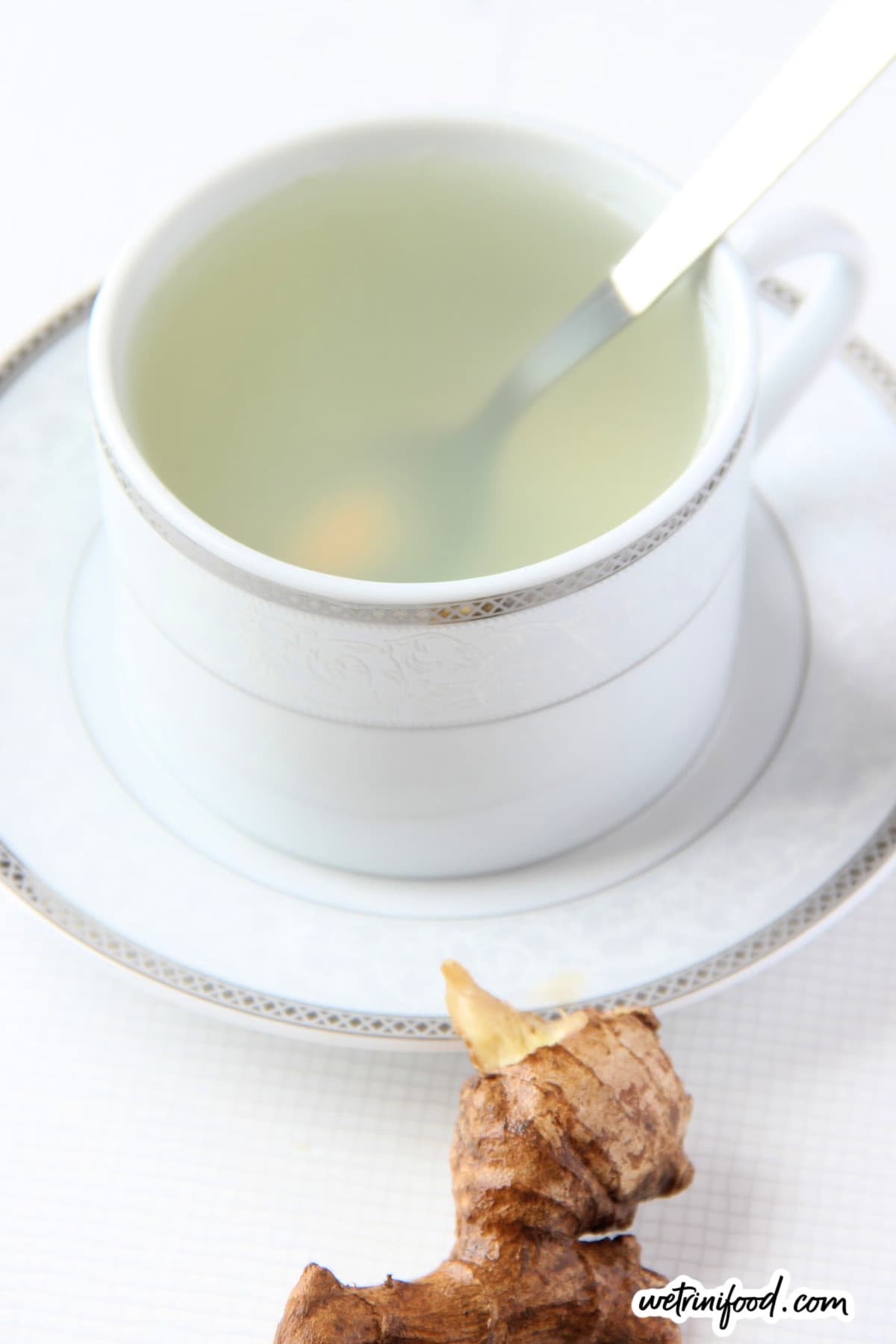 ginger tea in teacup with spoon and ginger on the side