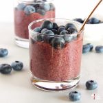 blueberry chia seed pudding in glasses with bronze spoons and blueberries on the side